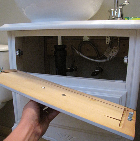 roller catches hold front of cabinet in place to allow access to plumbing