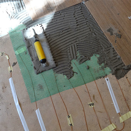 use notched trowel to apply tile adhesive to floor