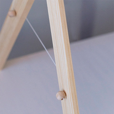 6. At the bottom 130mm centre mark, drill a 3mm hole. Tie one wooden bead to the end of a length of string, thread through the front of a hole in one leg, and through the back in the second leg. Repeat for the other side. Thread a wooden bead and tie off to create a string holder the both sides.