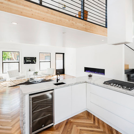 All-white interiors with white furnishings harmonize with the warm wood floors and beams, with black accents scattered throughout for visual impact.