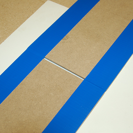 3. Lay strips of duct tape from the top of one panel to the bottom of the other, ensuring that the 5mm gap remains.