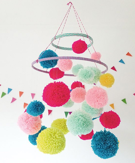 Use embroidery hoops and colourful pom-poms to make a unique mobile for a nursery