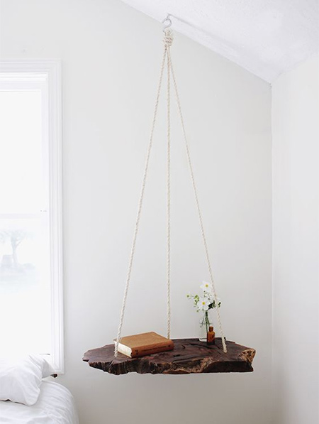 In a bedroom where space is limited, a hanging table takes up absolutely no floor space and is an easy DIY solution that you can make in an hour or two using a variety of materials.