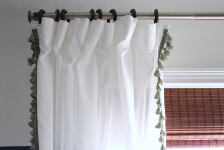 A layered window treatment consisting of bamboo Roman blind and white drapes
